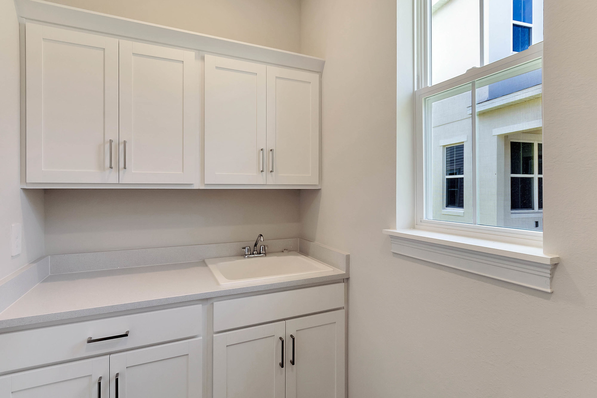 laundry room with white cabinets and sink